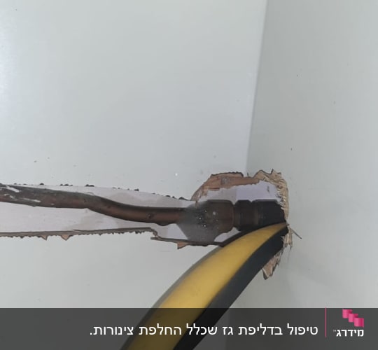 צינור גז צהוב ושחור יוצא מקיר לבן